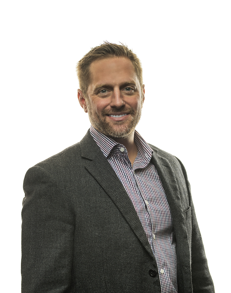 A man in a suit and tie smiling for the camera.