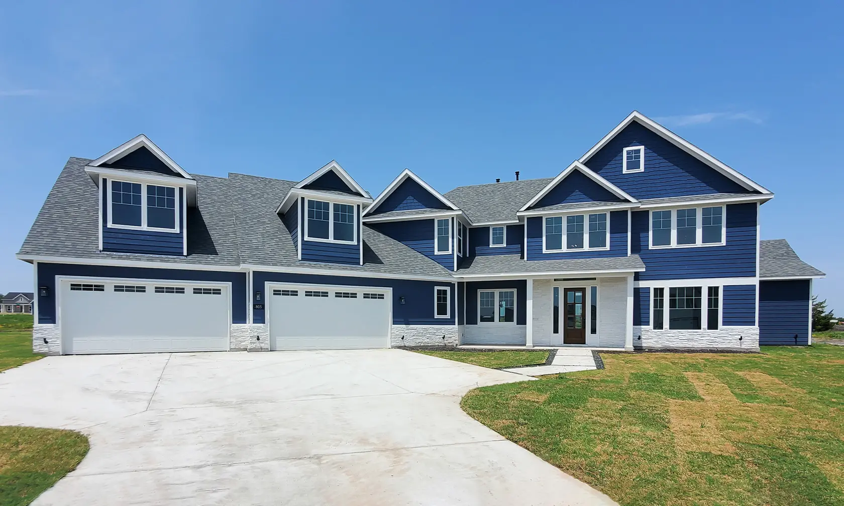 A large blue house with two garage doors.