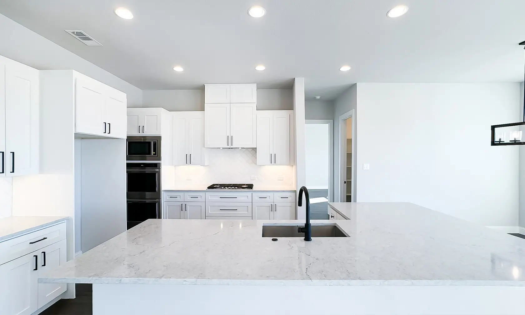 A kitchen with white cabinets and black appliances.