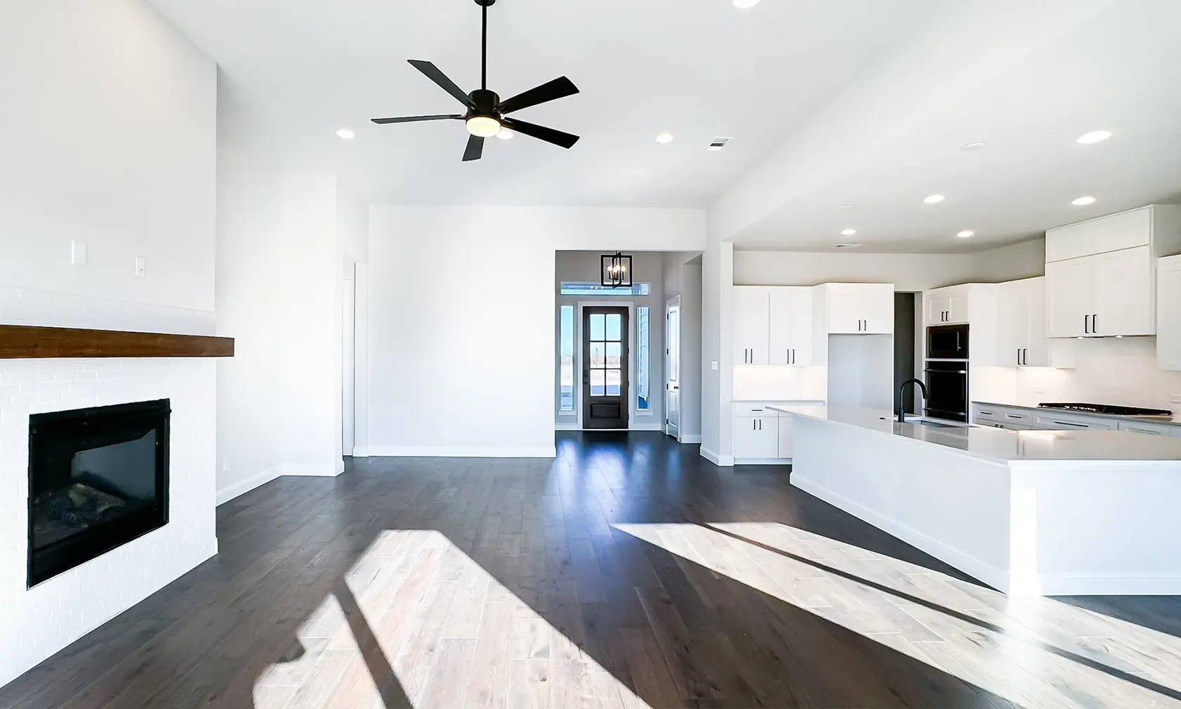 A room with a ceiling fan and hardwood floors.