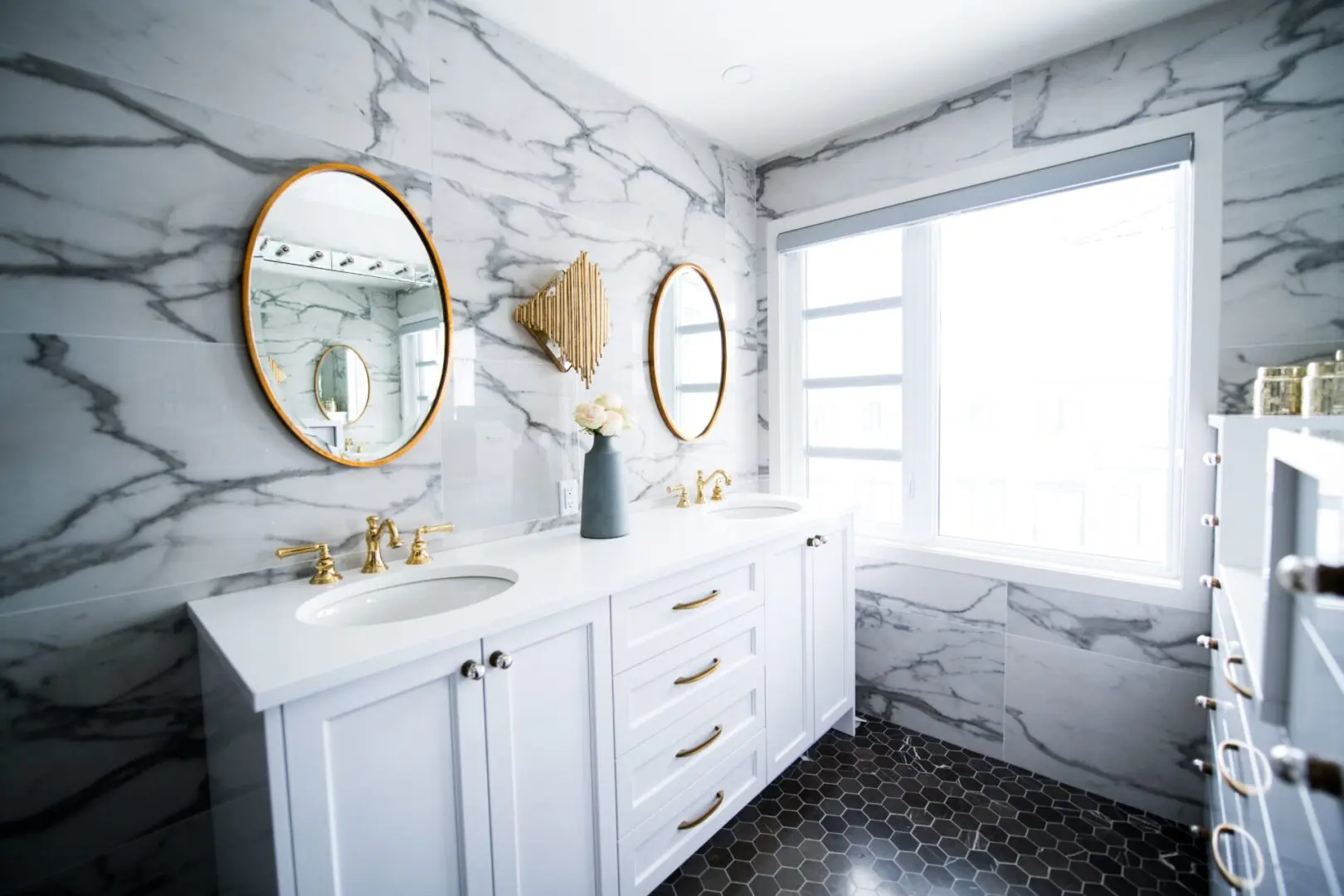 A bathroom with two mirrors and white cabinets.