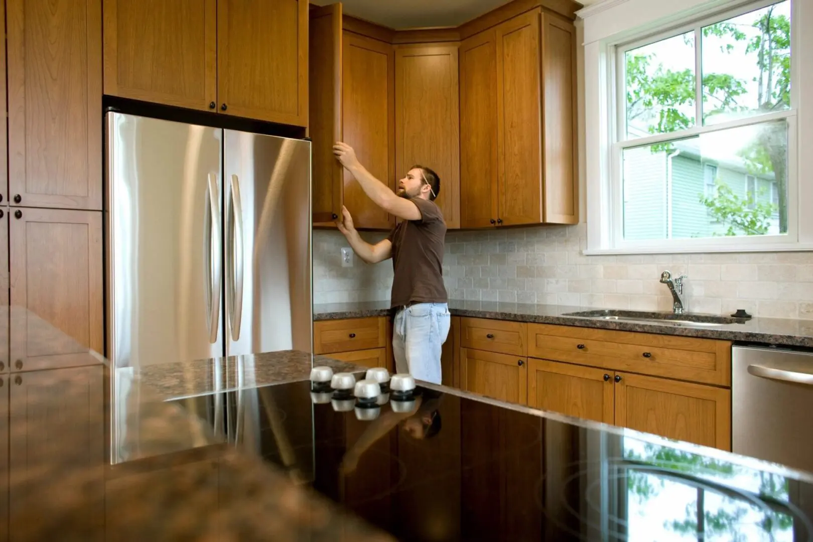 A man in brown shirt standing on top of kitchen counter.