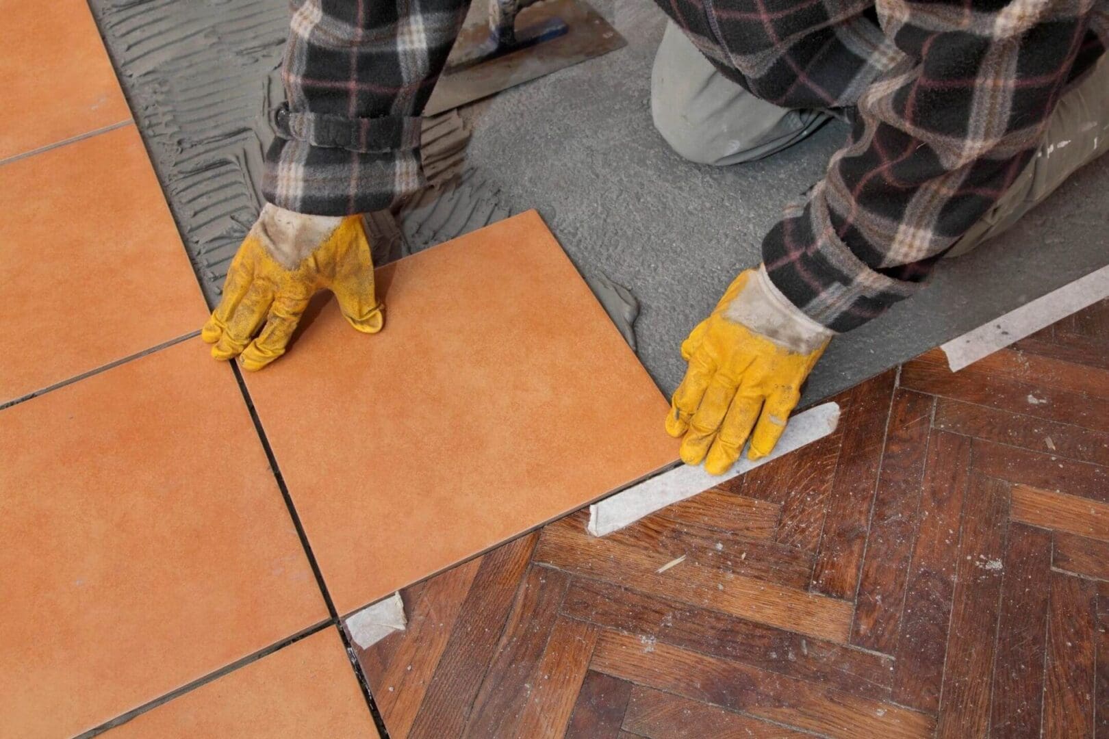 A person with yellow gloves on and some tiles